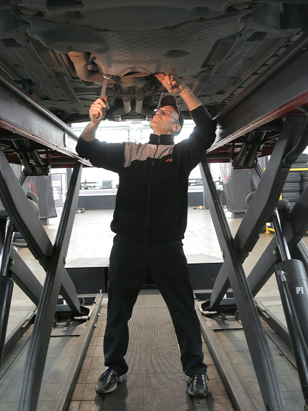 Mechanic under a vehicle on a lift